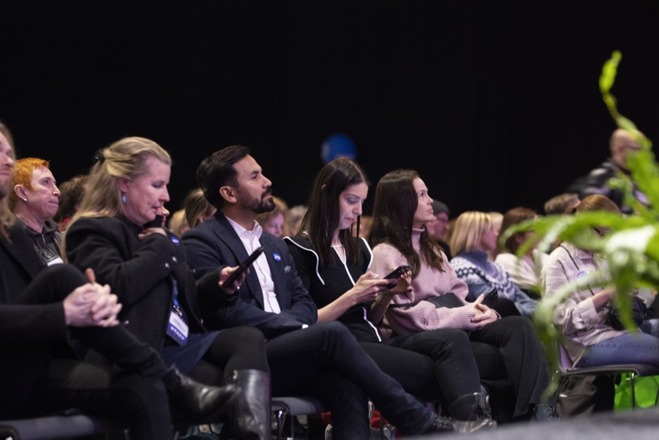 People sitting in a auditorium listening to a keynote speech